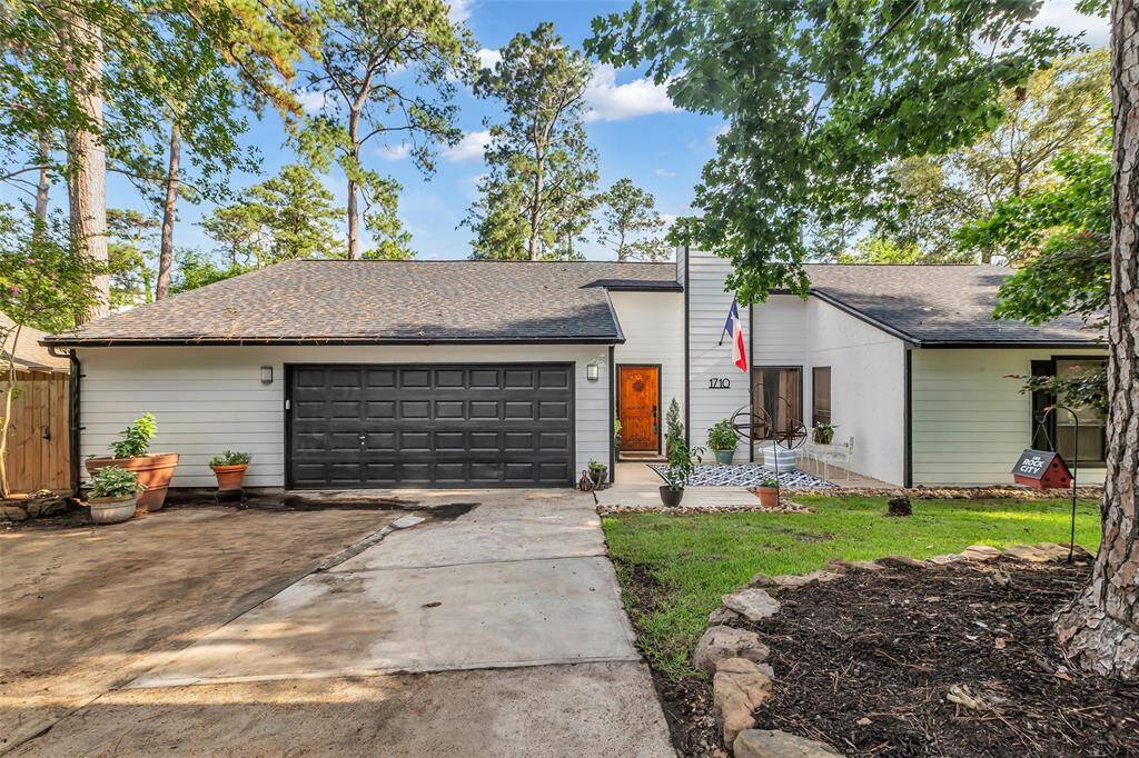 Full front of the home, including garage, patio, and surrounding trees. A picturesque introduction to this beautifully maintained Forest Cove gem.