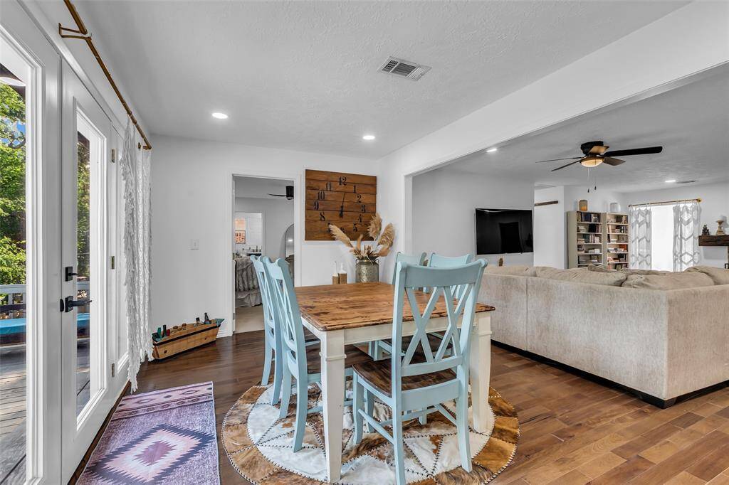 Charming dining space with French doors opening to the back deck, creating a seamless indoor-outdoor experience. Natural wood table and soft tones add rustic charm.