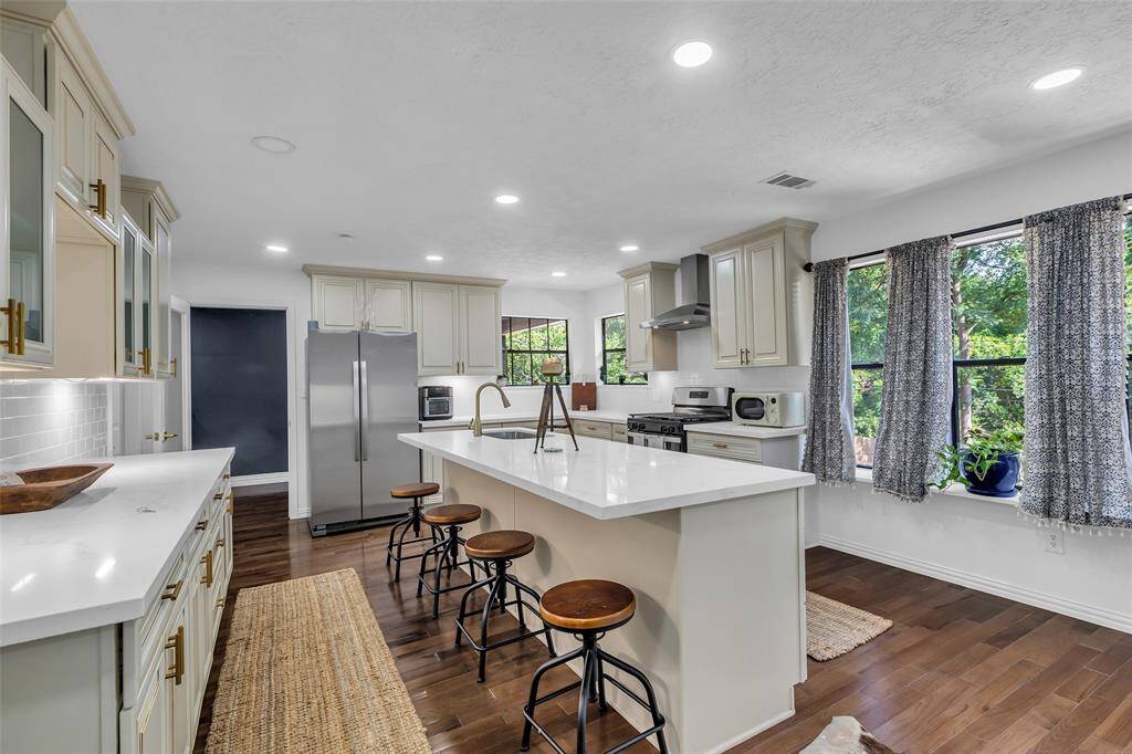 Bright and expansive chef’s kitchen with a massive quartz island, custom cabinetry, stainless steel appliances, and abundant natural light through large windows.