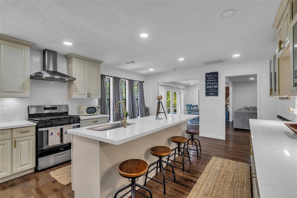 View of the island with bar seating, and open flow into dining and living areas. A true centerpiece of the home.