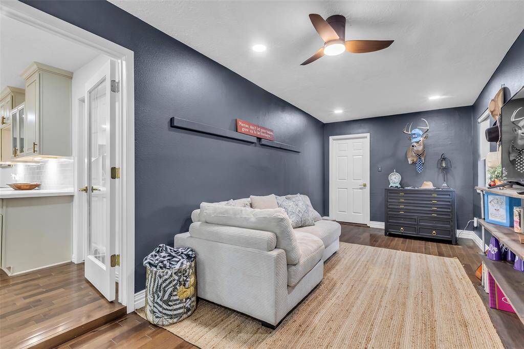 Cozy and versatile bonus room perfect for a study, playroom, or additional lounge. Features rich wood flooring, recessed lighting, and access to the kitchen.