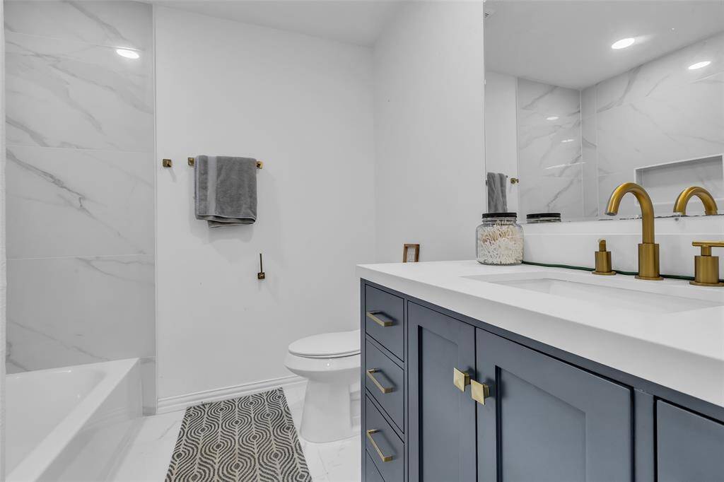 Gorgeously updated full bathroom, elegant gold fixtures, and porcelain tile shower surround. Stylish and functional.