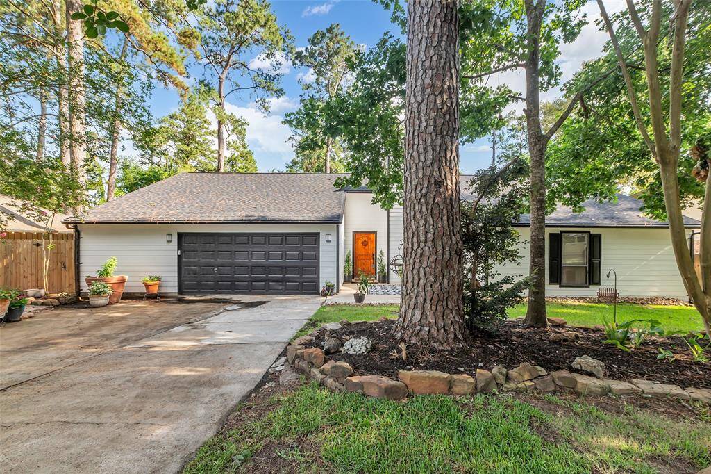Another front-facing view of the home showing off the natural setting, established trees, and fresh exterior paint with modern contrast trim.