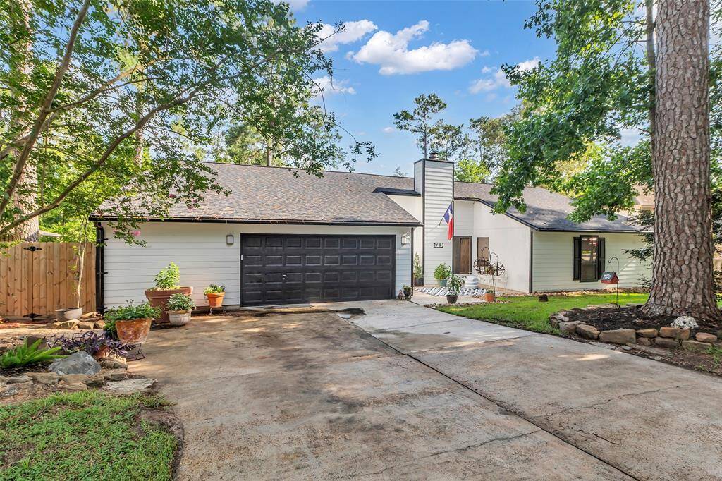 Front view of the home with a clean concrete driveway, updated black garage doors, and tasteful landscaping. Great curb appeal in a quiet, tree-lined street.