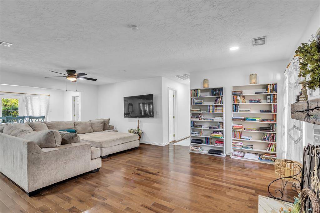 Alternate angle of the open-concept living room showing built-in bookshelves, abundant windows, and a comfortable, inviting atmosphere.