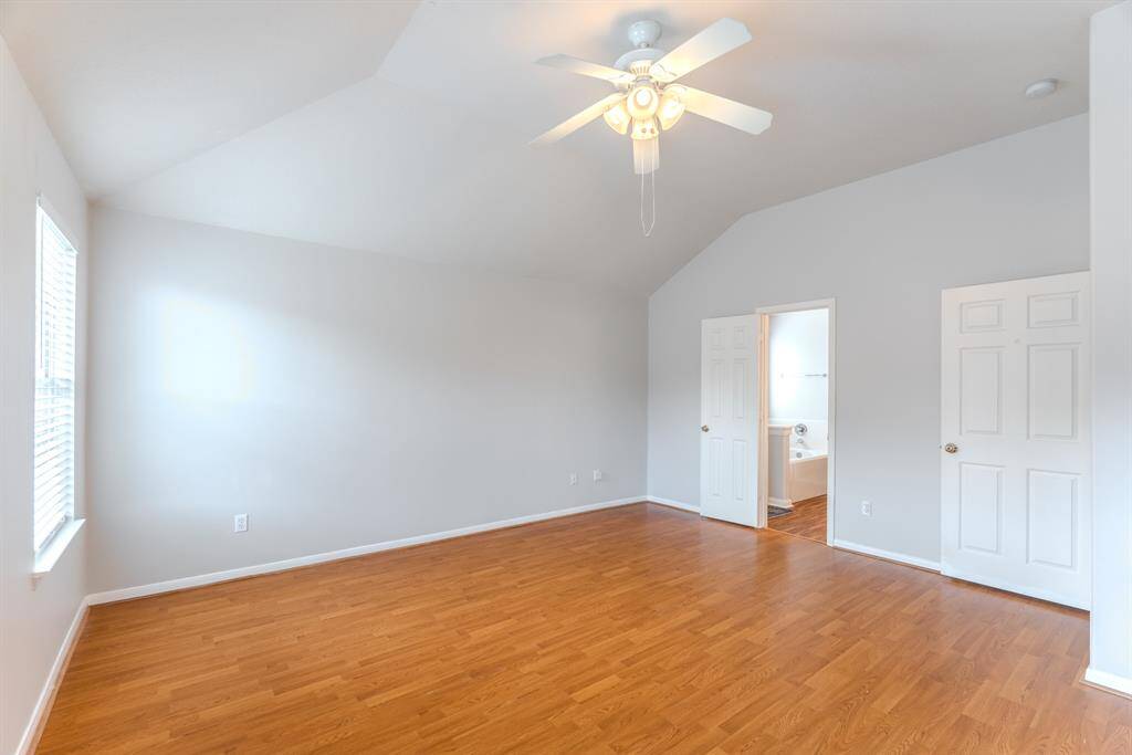 The primary bedroom offers high ceilings, abundant natural light, and direct access to the en-suite bathroom and walk-in closet