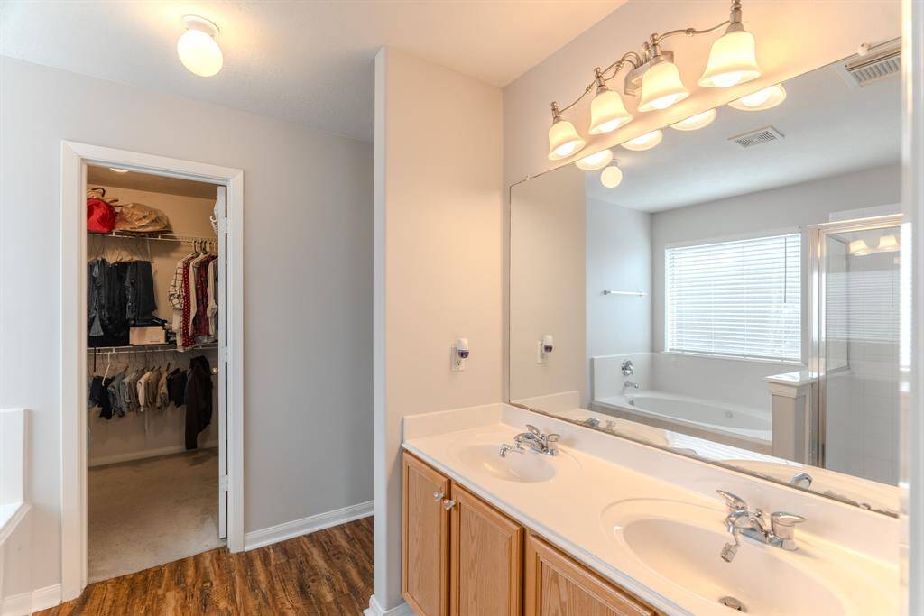The primary bathroom features dual sinks, a soaking tub, and a separate shower, all seamlessly connected to the walk-in closet for added convenience