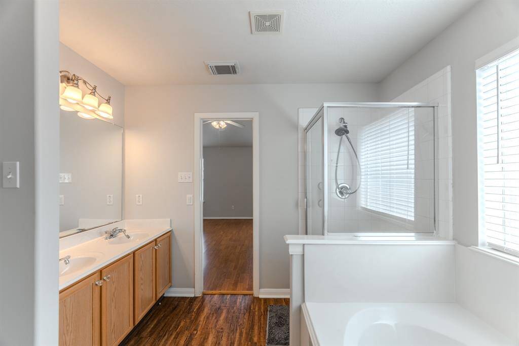 The primary bathroom features dual sinks, a soaking tub, and a separate shower, all seamlessly connected to the walk-in closet for added convenience