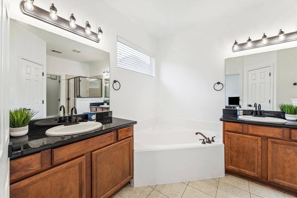 Primary bathroom with twin basins and vanities, cabinet storage and a wonderful soaking tub.
