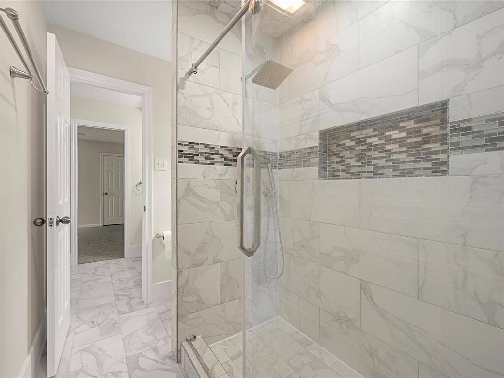 Updated walk-in shower featuring a built-in soap niche and sleek stainless steel shower head