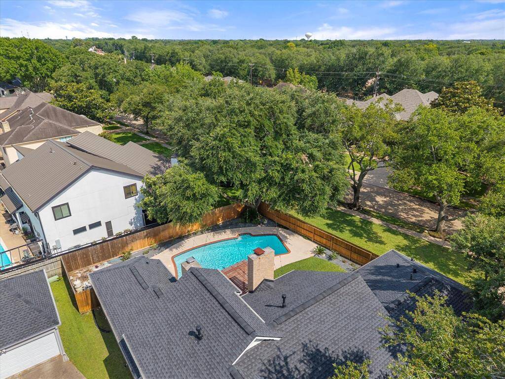 A stunning drone view captures the full beauty of this custom-built property—highlighting the elegant architecture, sparkling pool, spacious backyard, and charming pergola, all set within the well-established Sugarwood community.