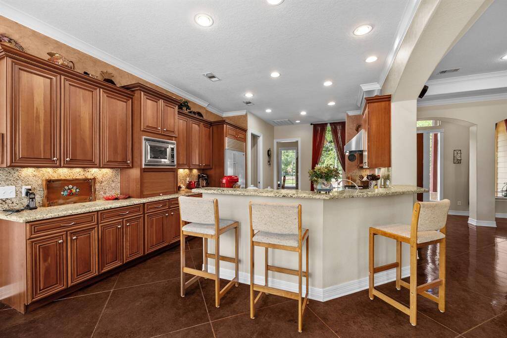 Granite-topped peninsula offers casual seating for three, generous prep space, and seamless sightlines into the family room and dining nook.