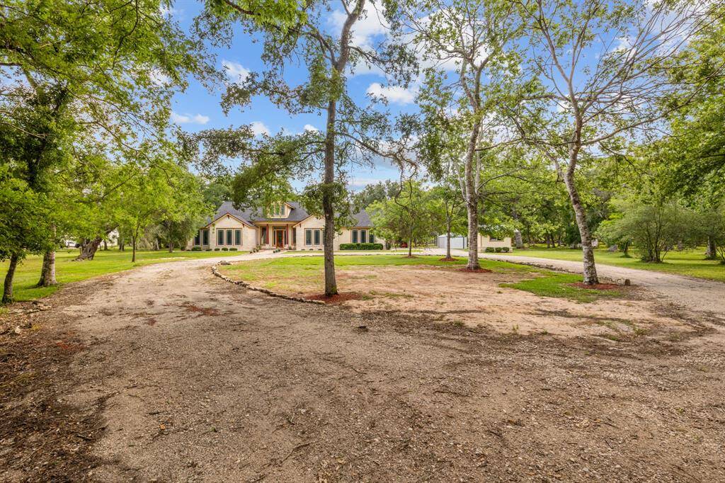 Gently curving gravel drive leads straight to the front door, flanked by mature oaks and manicured lawn.