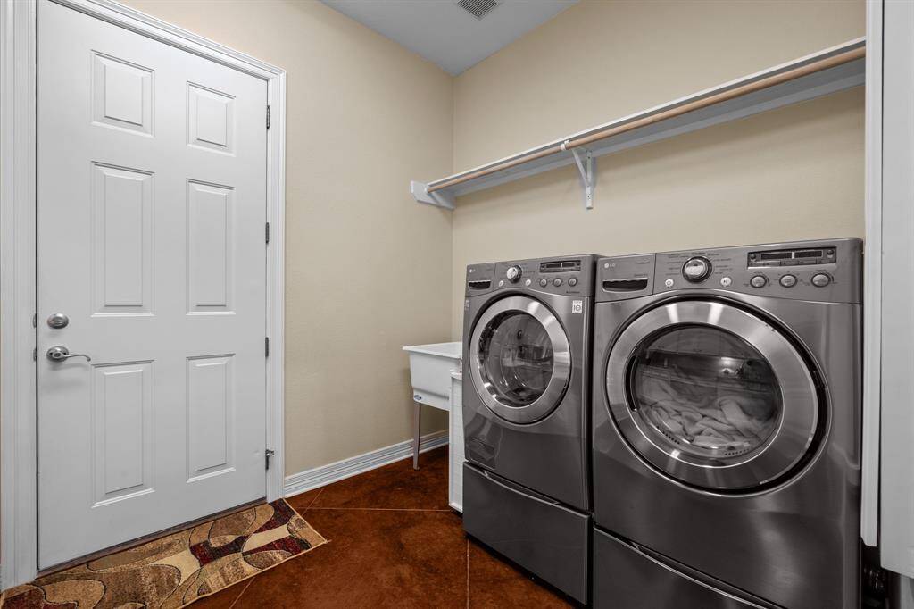 Space for a Front-load washer/dryer set under a hanging rod, with a deep utility sink and direct garage access for ultimate household convenience.