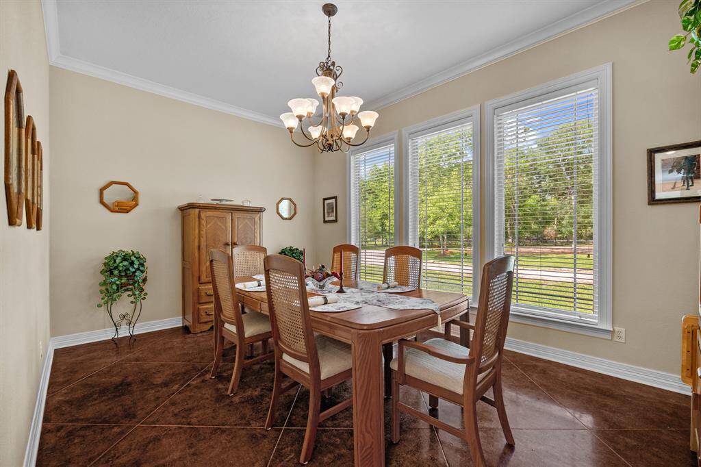 Elegant formal dining space anchored by three wall-to-wall windows that showcase sweeping views of the manicured front lawn.