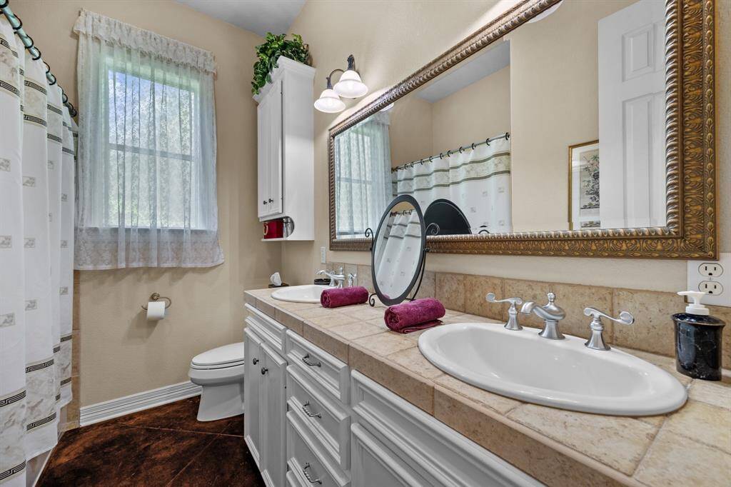 Bright bath with dual vanities, tile countertop, and a full-height tub/shower combo.