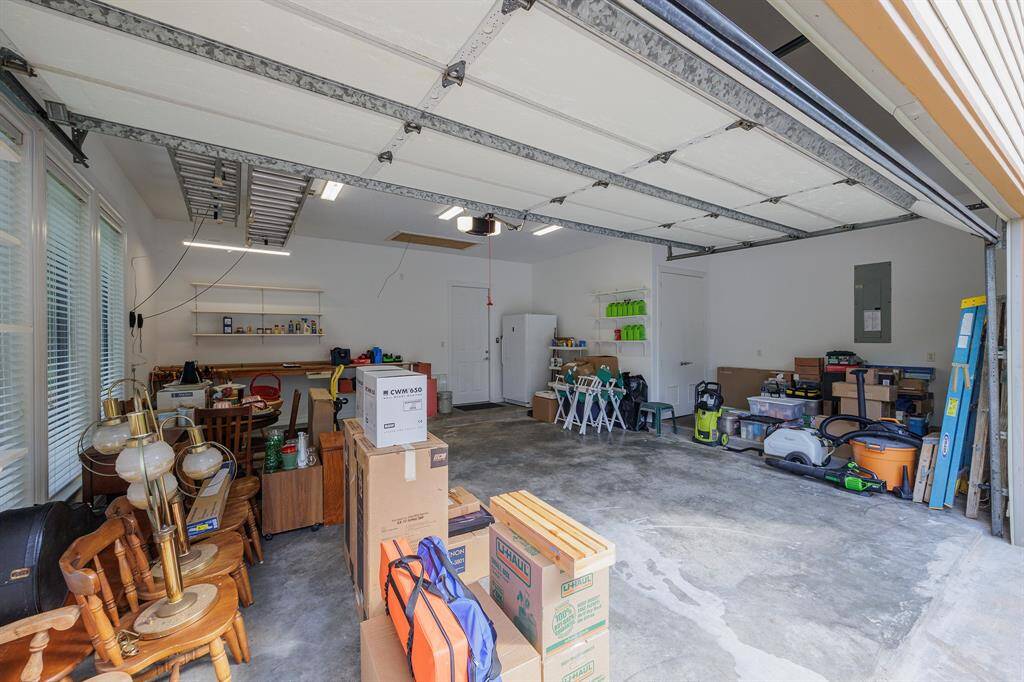 Spacious two-car attached garage featuring concrete floors, workbench, wall shelving, plentiful natural light and direct house access. Large extended area for massive amounts of storage.