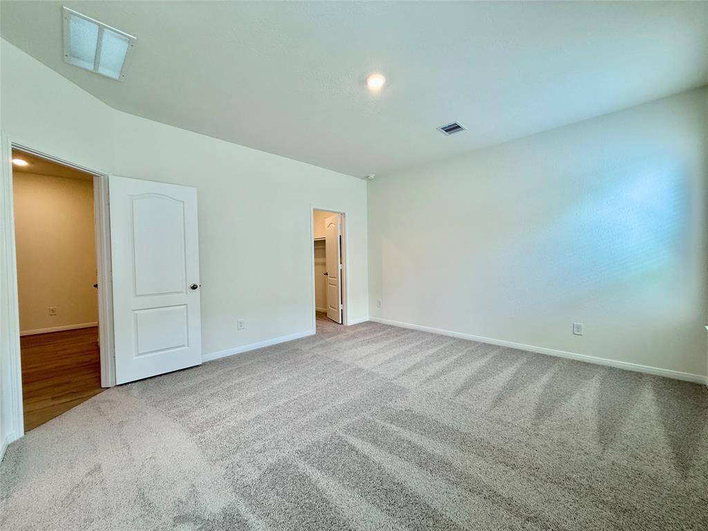 Spacious primary bedroom with two large windows and easy access to a roomy closet.