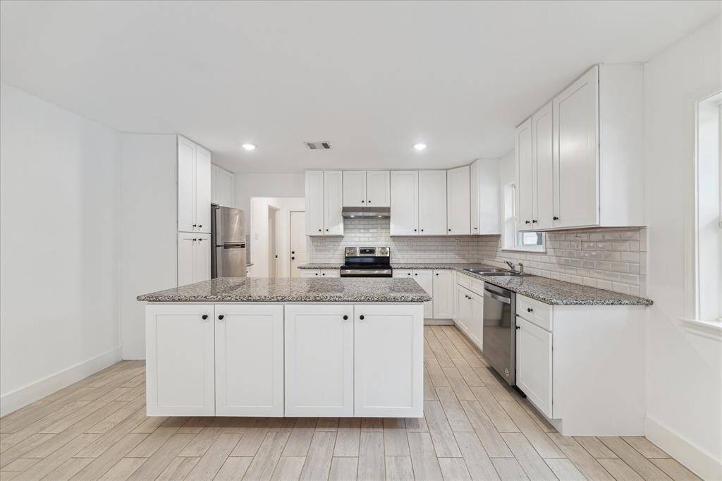 Fully updated kitchen with stainless appliances, granite countertops, white subway tiles and ample cabinet space. Just past refrigerator is a nice office/bonus room and the entrance to the attached garage.