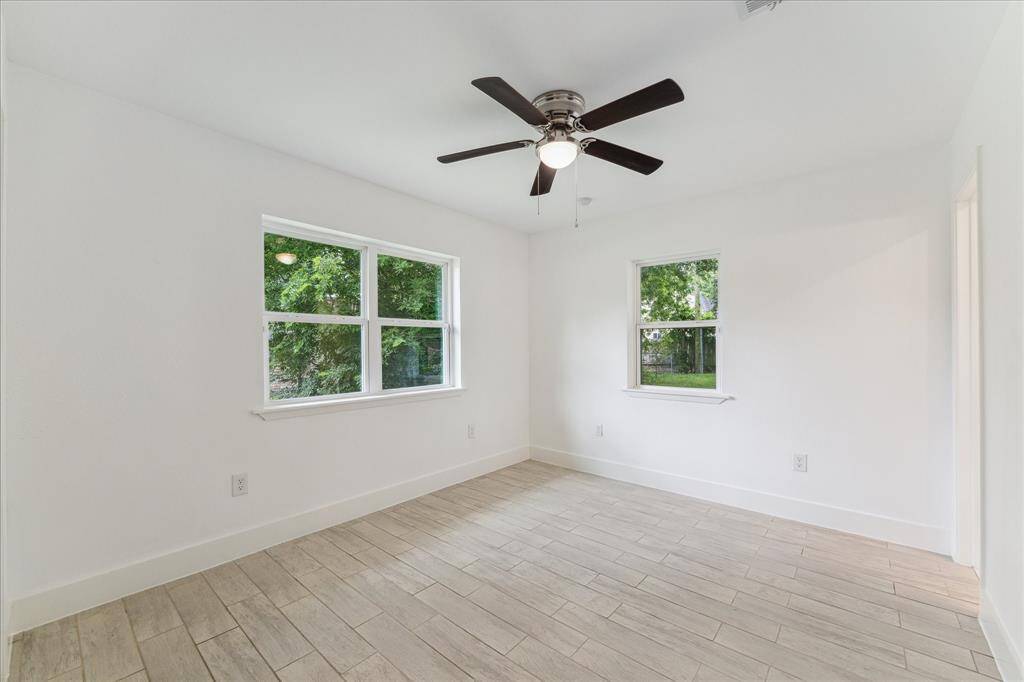 The primary bedroom  has an ensuite bath, windows on two walls looking to the backyard and a new ceiling fan.
