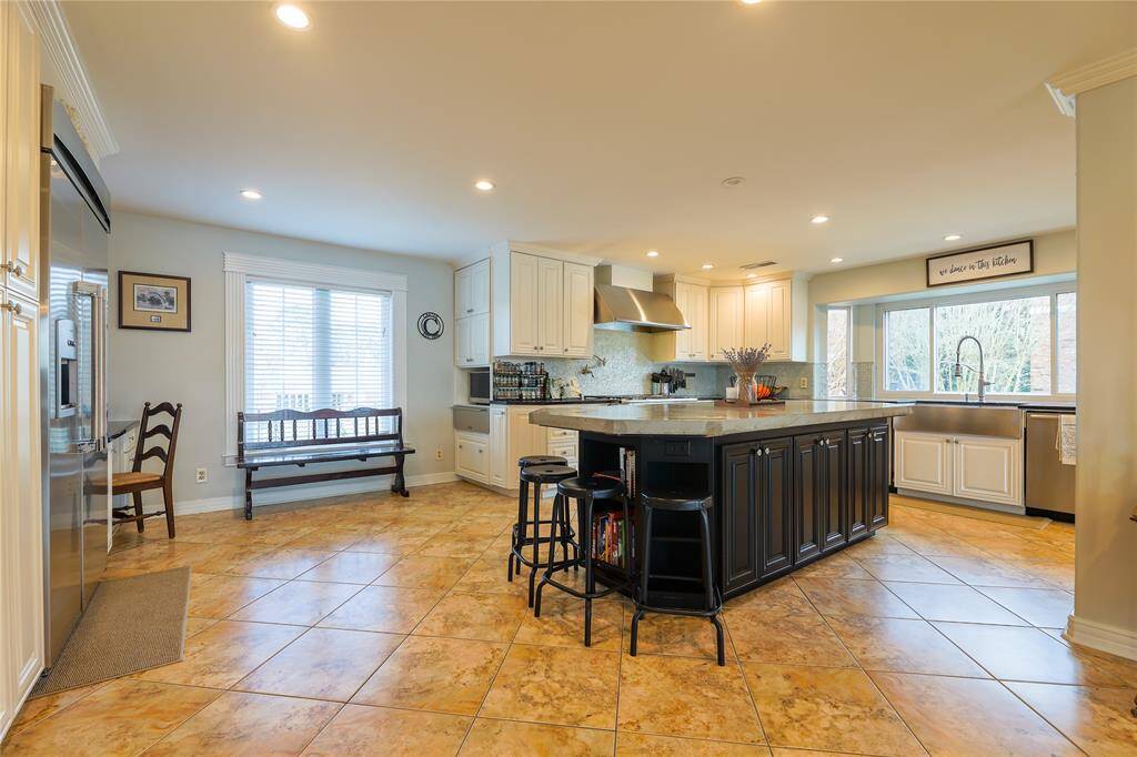 This spacious kitchen features a large central island with seating, high-end stainless steel appliances, and ample cabinetry.