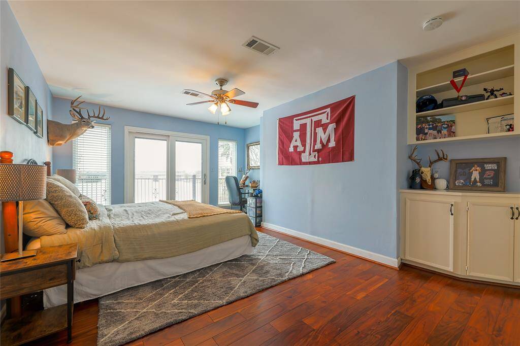 This photo shows a cozy bedroom with light blue walls and hardwood floors. Built-in shelves and a display of personal items add character to the space.