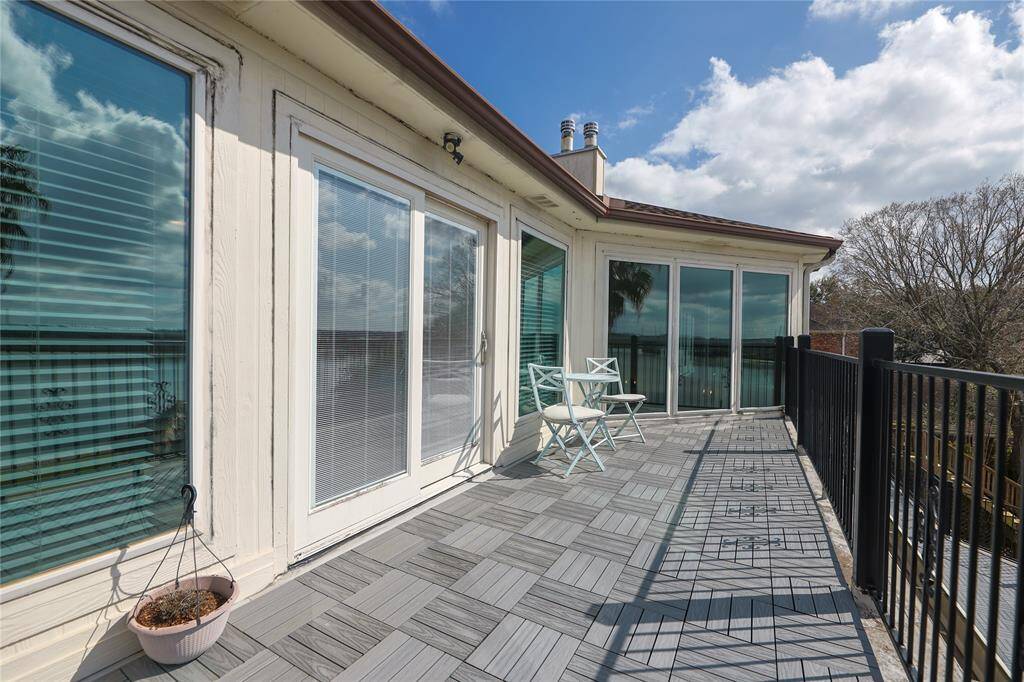This photo showcases a spacious, sunlit balcony with TechWood UltraShield deck tiles, installed for lightness and durability, along with large glass doors—ideal for relaxation!