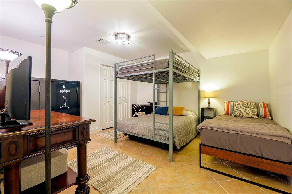 This room features a versatile setup, perfect for maximizing sleeping space. It has tiled flooring and ample lighting, ideal for a guest room.