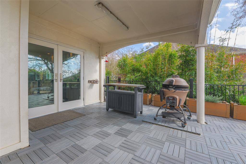 This photo showcases a covered patio. Room for a grill and a prep station. The space is accented with planters and offers a view of the surrounding greenery, ideal for outdoor entertaining.