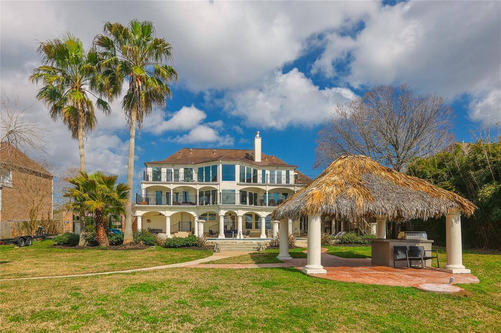 The beautifully landscaped yard includes tall palm trees, a charming thatched-roof gazebo and built-in grill, perfect for outdoor entertaining.