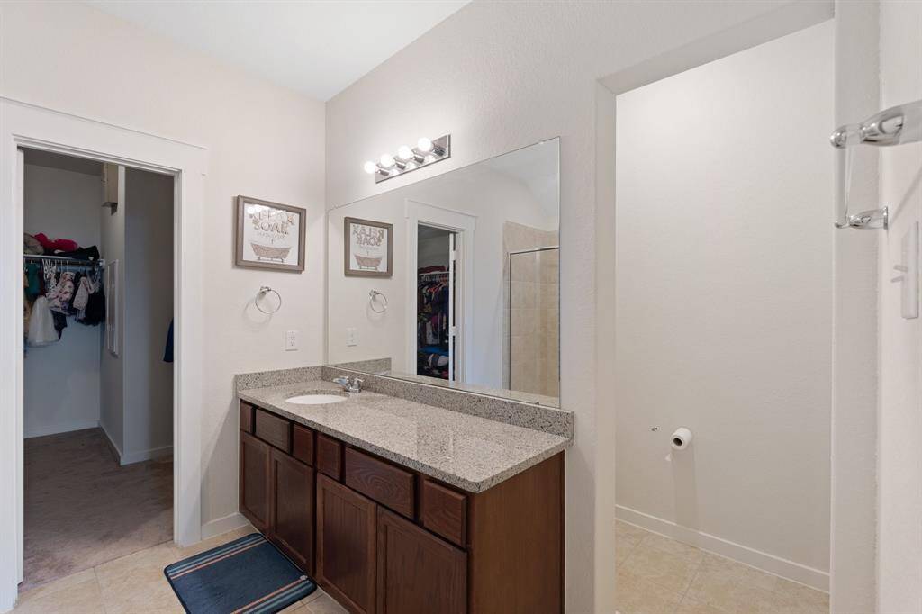 Additional view of the primary bathroom featuring a spacious walk-in closet, oversized mirror and sleek finishes throughout.