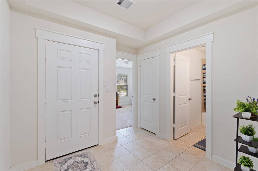 Convenient hallway with tile flooring that leads to the full bathroom, spacious bedroom, and access to the garage. A handy storage closet along the way ensures there's plenty of space to keep your essentials organized and within reach.