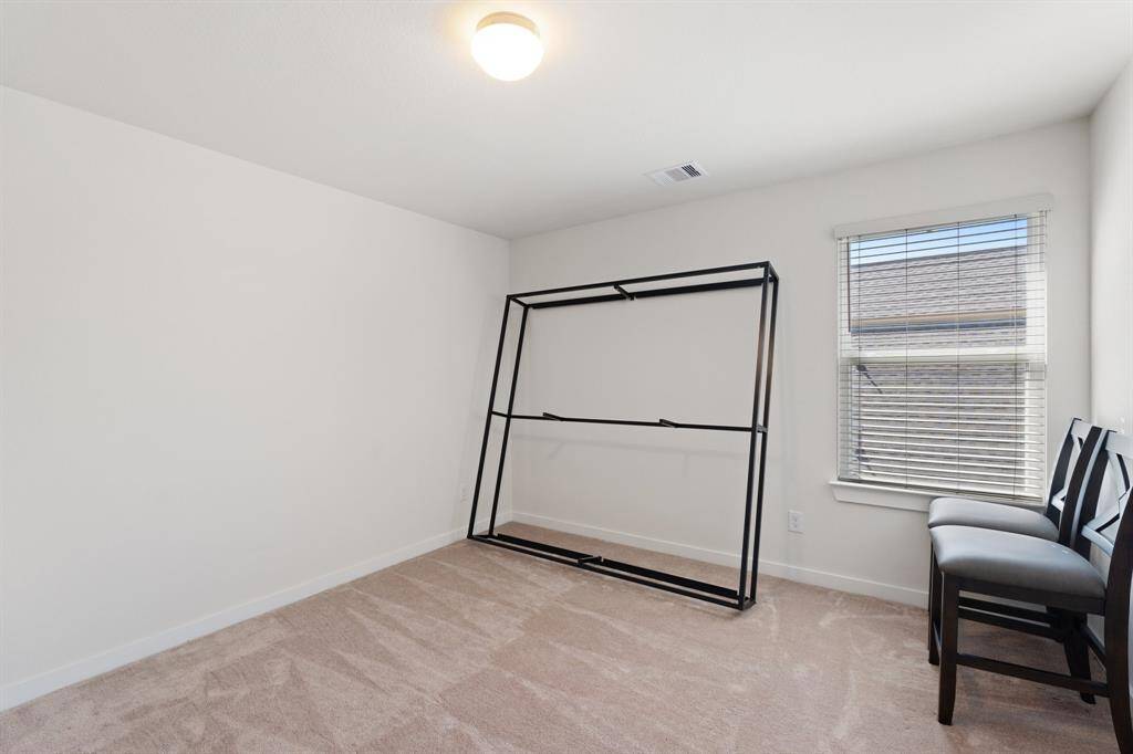 Main floor secondary bedroom, ideal for multi-generational living. Featuring an oversized window, plush carpet, and neutral finishes, this suite creates a welcoming and serene atmosphere.