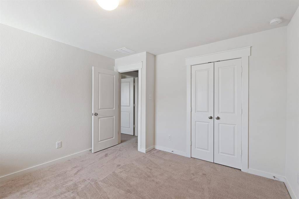 Additional view of the secondary bedroom on main floor, offering privacy with a nearby bathroom. This cozy retreat is perfect for multi-generational living or guests.