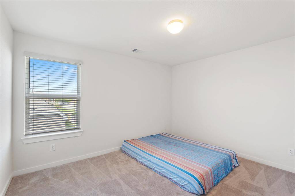 Charming secondary bedroom with oversized window, plush carpet, and easy access nearby bathroom, perfect for shared living.