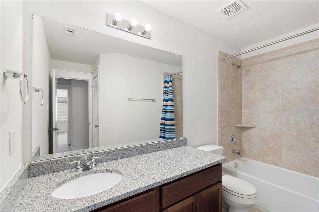 Full bathroom on second floor offering sleek countertops, an oversized mirror, and warm cabinetry. A bright, airy space with ample storage that combines style and practicality.