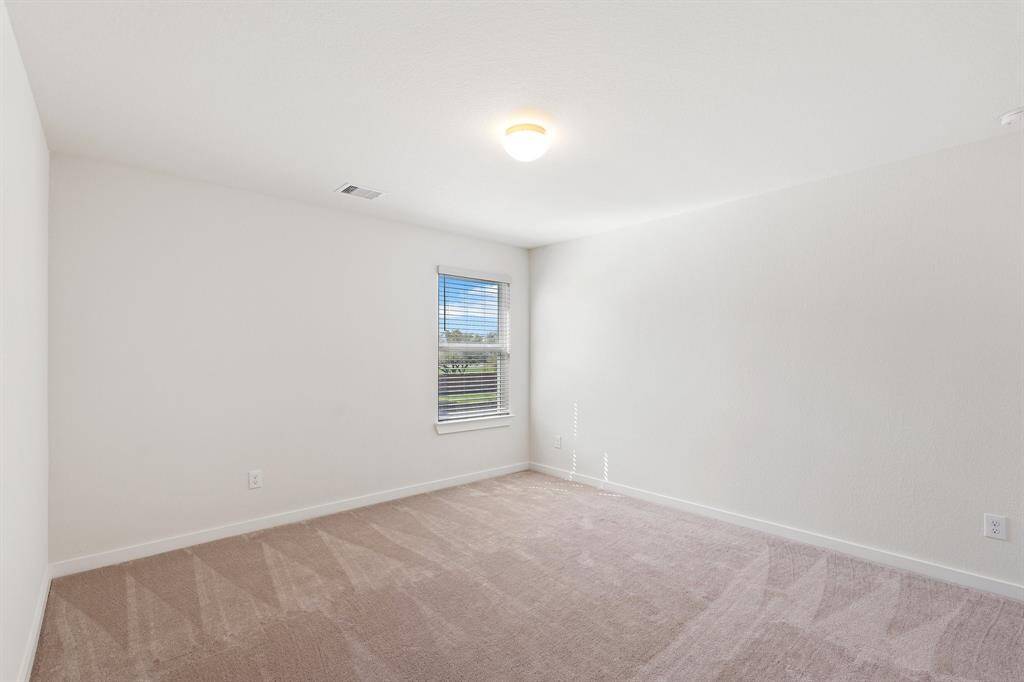 Spacious secondary bedroom featuring a walk-in closet, oversized window, and convenient access to a nearby bathroom. Natural light fills the space, creating a bright and inviting atmosphere.