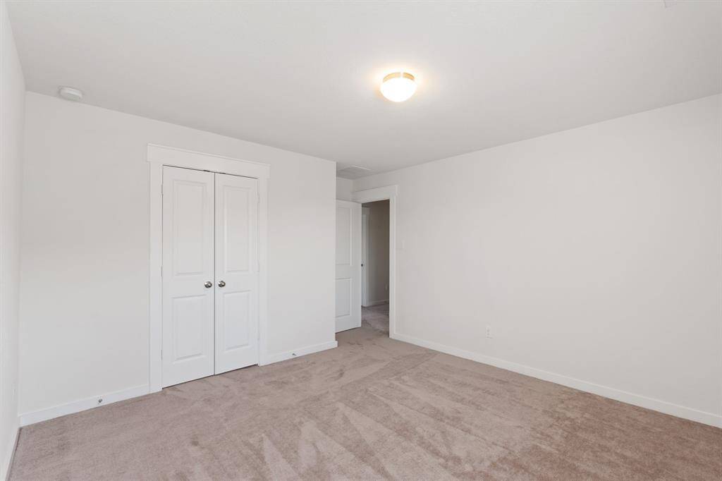 Additional view of the Spacious secondary bedroom featuring a double-door closet, oversized window, and convenient access to a nearby bathroom.