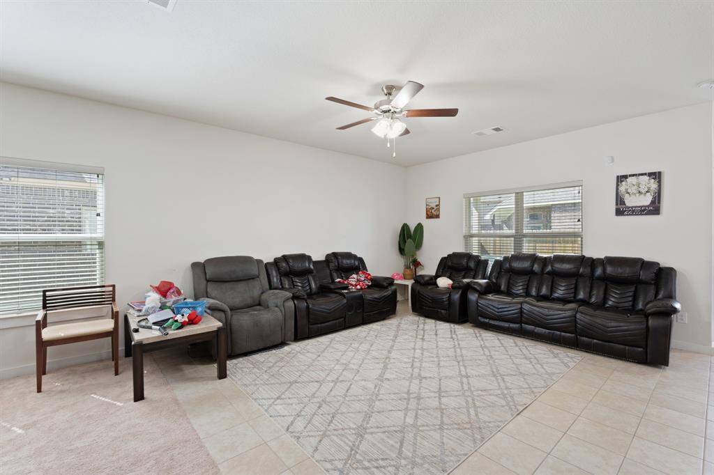 Bright and airy living room with sleek tile flooring and a picturesque window offering a view of the serene backyard. This space opens directly into the kitchen and dining area, creating a seamless flow perfect for both relaxed living and entertaining.
