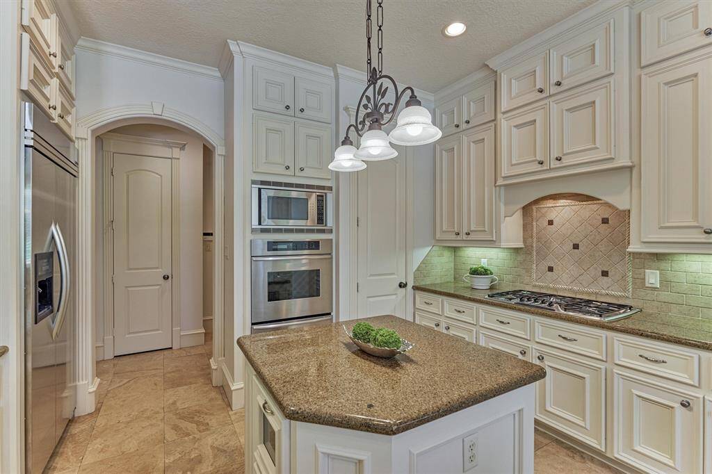 Counter-to-ceiling cabinets for optimal storage, including a matching wood hood for perfect symmetry. Note the arched, wood-trimmed opening to a back hallway that ideally serves as a pass-through to the dining roomand tucked away mud/utility room.