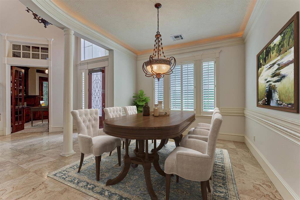 Open formal dining room is flanked with pillars and boasts wraparound molding and plantation shutters. Imagine entertaining family and friends in this gorgeous space! *This photo is virtually staged*