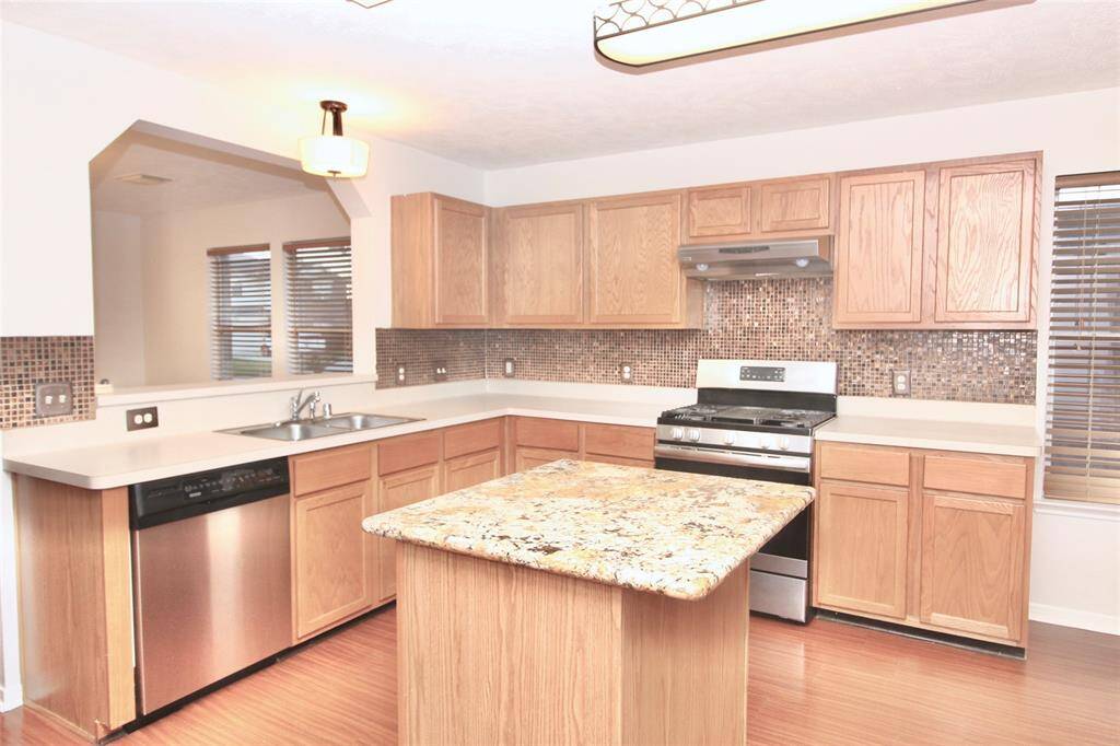 View of the island kitchen with stainless steel appliances and refrigerator included.