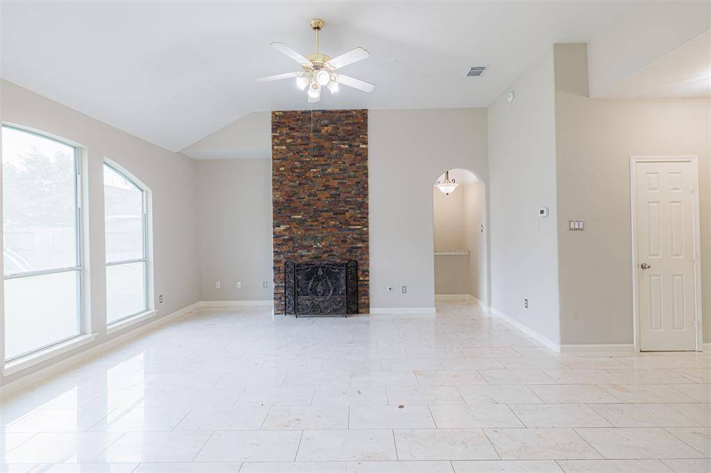 A spacious family room with high ceilings, fireplace, and a wall of windows overlooking the backyard.