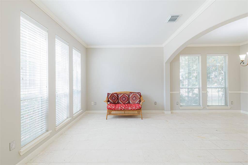 Formal living area features marble flooring, crown molding and a wall of windows making the space light and bright.