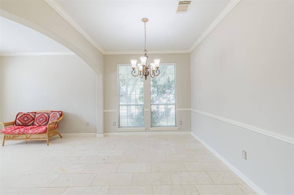 Formal dining room with marble flooring, crown and chair rail molding.