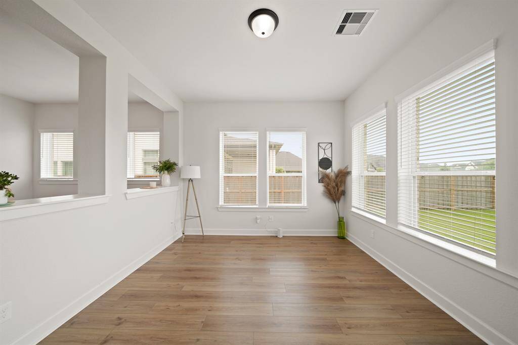 Bright and inviting room with large windows, neutral walls, and wood flooring. It features an open layout with a view to the outside, creating a spacious feel. Perfect for a sunroom.