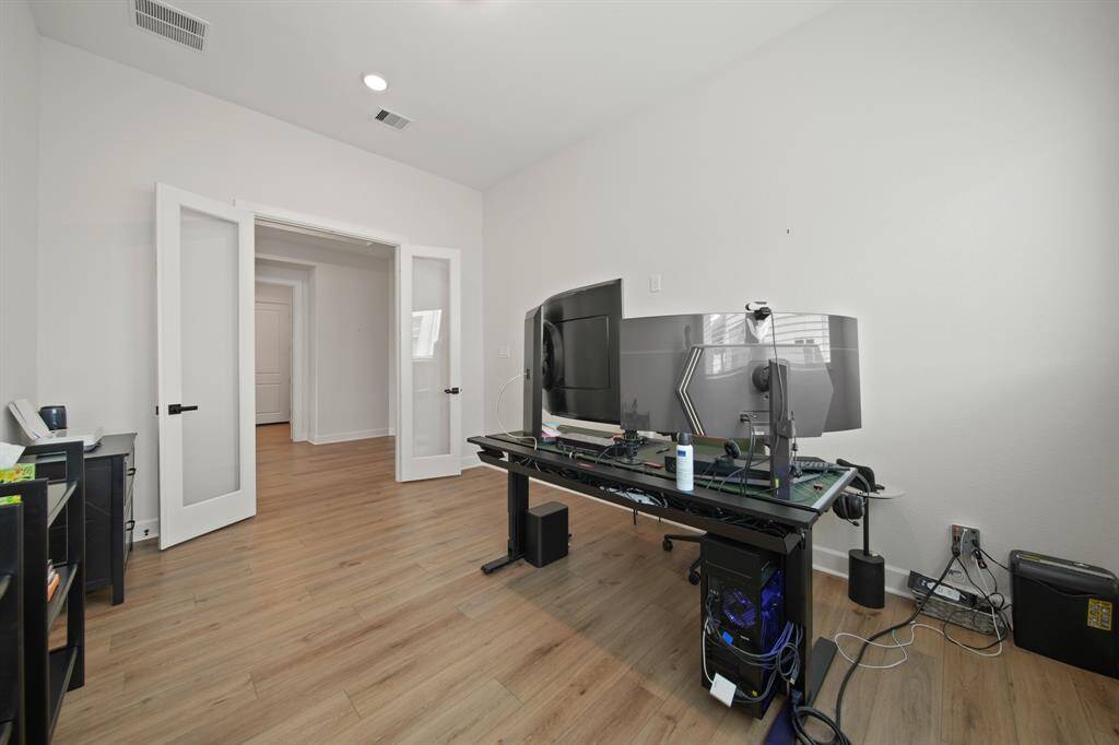 This photo shows a well-lit, modern home office with wood flooring..The room is spacious and ideal for remote work.