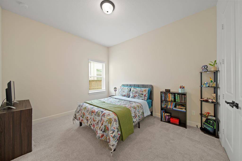 This bedroom is cozy and bright, featuring neutral walls, a window for natural light, and carpeted flooring, making it ideal for a child or guest room.