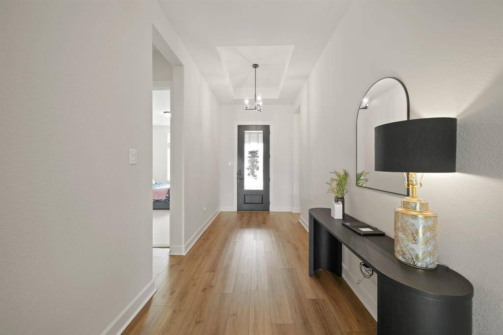 This photo showcases a modern, well-lit entryway featuring sleek wood flooring and neutral walls.