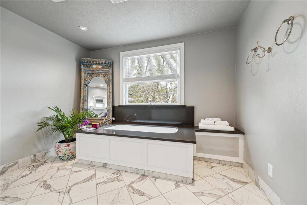 Spa-like Primary Bath boasts a peaceful soaking tub by Waterworks.